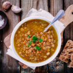 meatless meal with lentil soup in a white bowl, topped with cilantro and with a side of crackers