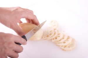 person cutting up lotus stem for a lotus stem recipe