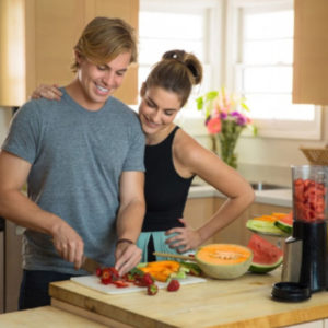 man and woman couple cutting up watermelon and cantaloupe for a smoothie following tips for healthy eating