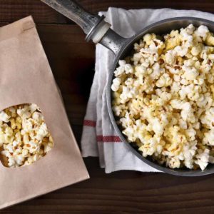 Top view of a bag of gourmet popcorn next to a pot of freshly popped corn for popcorn bar ideas