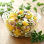 mango salsa in bowl with cilantro leaves