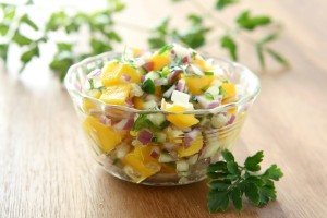 mango salsa in bowl with cilantro leaves