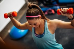 women at gym with free weights following a weight lifting routine