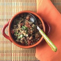 lentil salad with tomato feta and herbs in an orange bowl