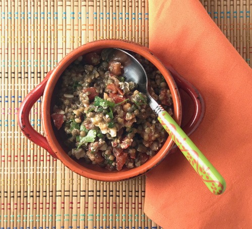 lentil salad with tomato feta and herbs in an orange bowl