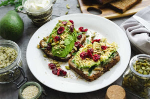 avocado toast with colorful toppings for phytonutrients and plant compounds on a white plate