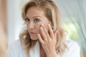 Woman looking in the mirror for fine lines after taking collagen supplements