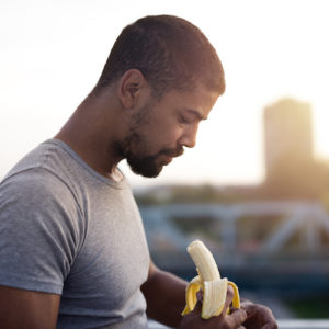 black man holding a banana before a run for nutrition for runners